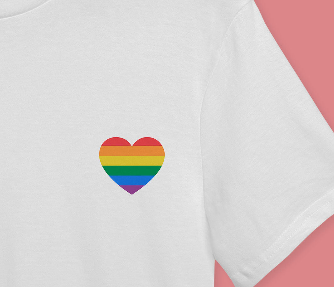 A close up image of the white t-shirt with the six colour pride rainbow heart on the right hand side of the chest.